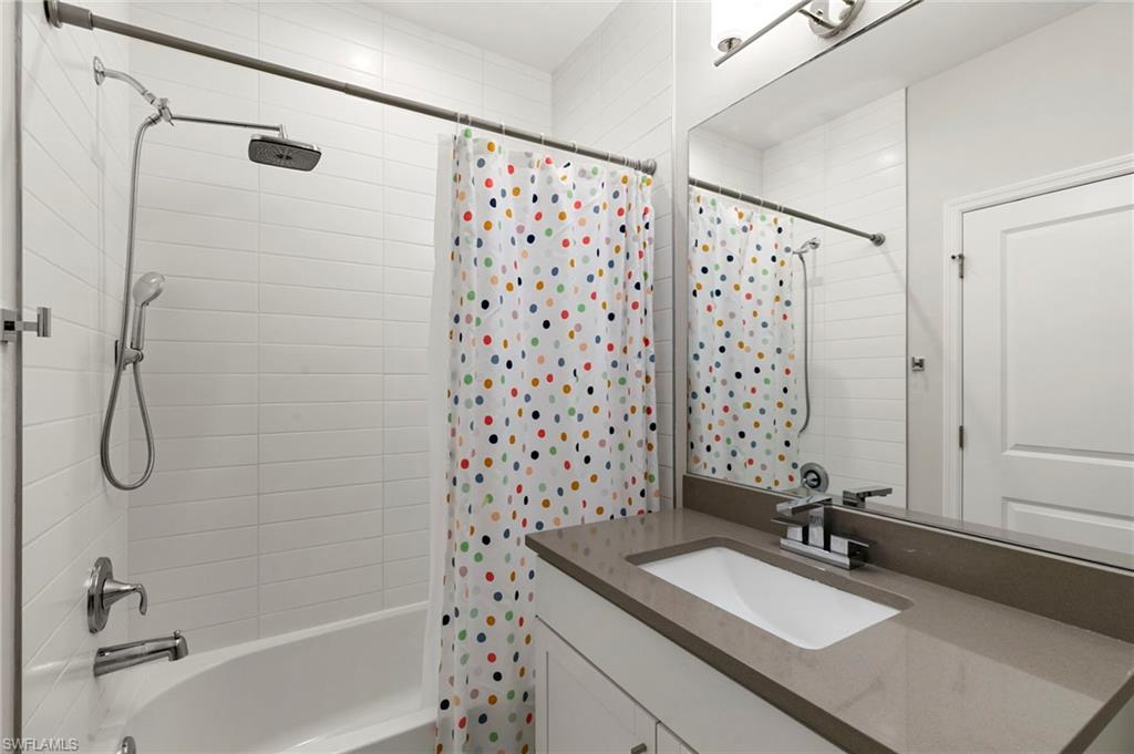 7421 Rockefeller Drive Naples, FL 34119 - Photo 23 of 37 a bathroom with a granite countertop sink a mirror a shower and a bath tub