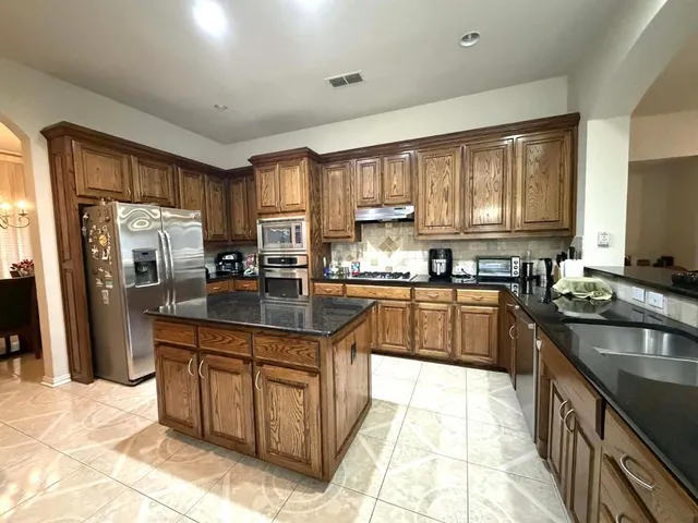 a kitchen with stainless steel appliances granite countertop a stove top oven a sink dishwasher a refrigerator and cabinets with wooden floor