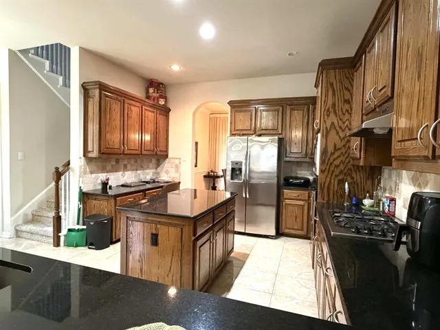 a kitchen with stainless steel appliances granite countertop a refrigerator a stove and a sink