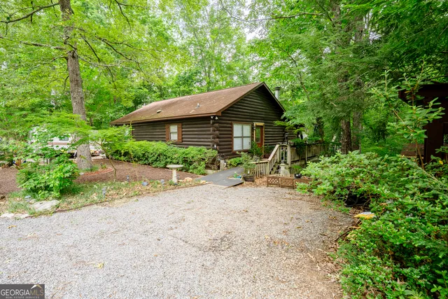 a view of a house with a small yard plants and a large tree