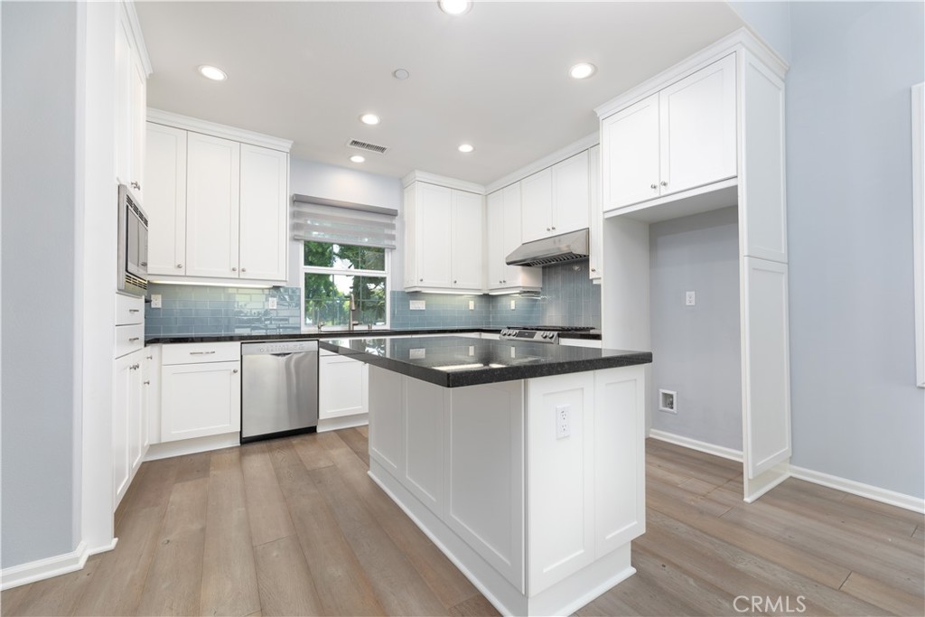 242 Firefly Irvine, CA 92618 - Photo 5 of 24 a kitchen with stainless steel appliances granite countertop a sink a stove a refrigerator and white cabinets