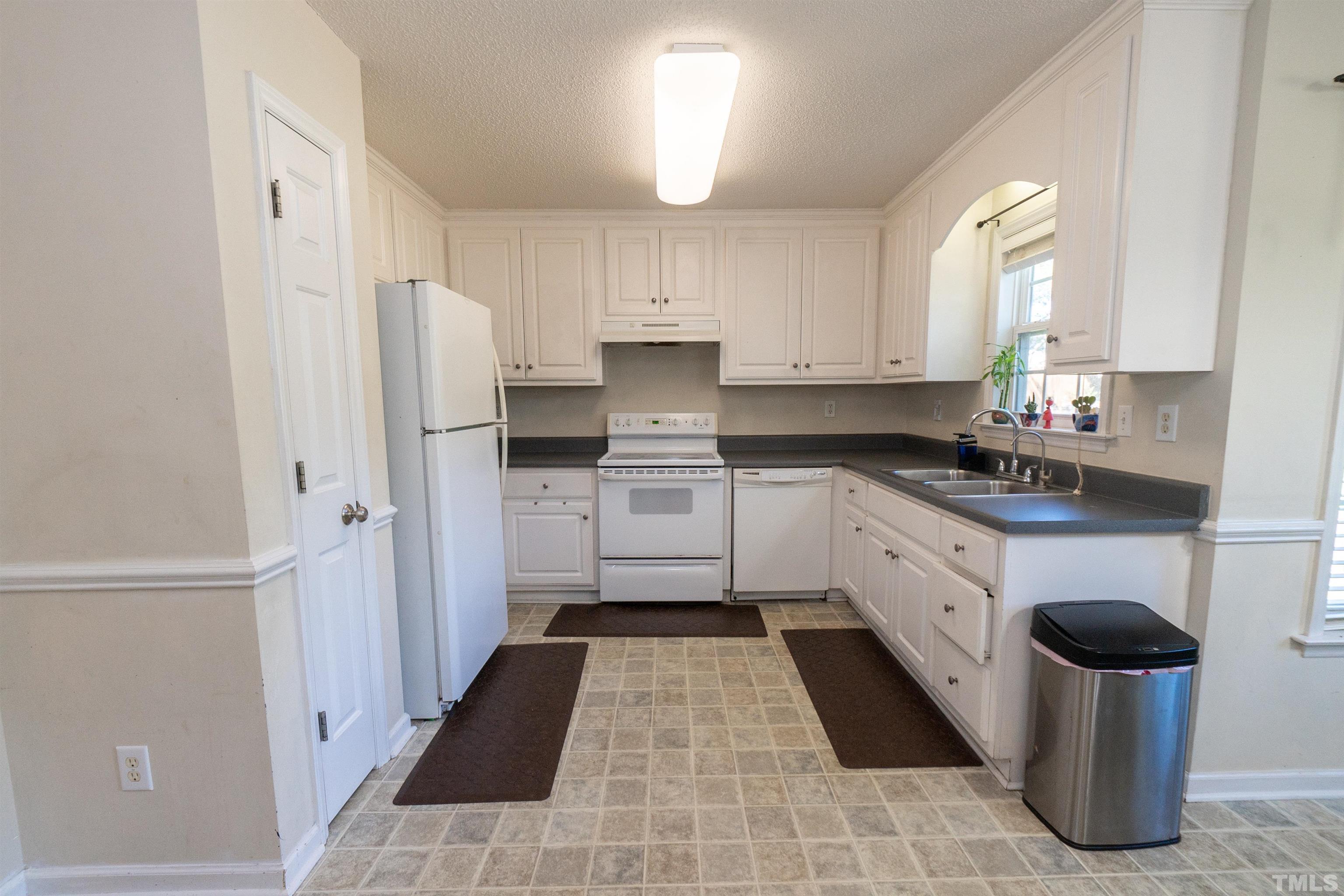 128 Edmondson Drive Willow Spring, NC 27592 - Photo 12 of 24 a kitchen with stainless steel appliances a refrigerator sink and white cabinets