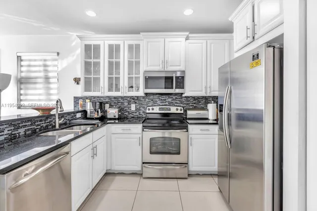 a kitchen with a refrigerator sink and cabinets