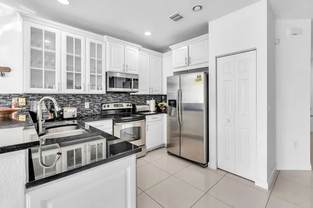 a kitchen with stainless steel appliances granite countertop a refrigerator a stove a sink and a granite counter tops