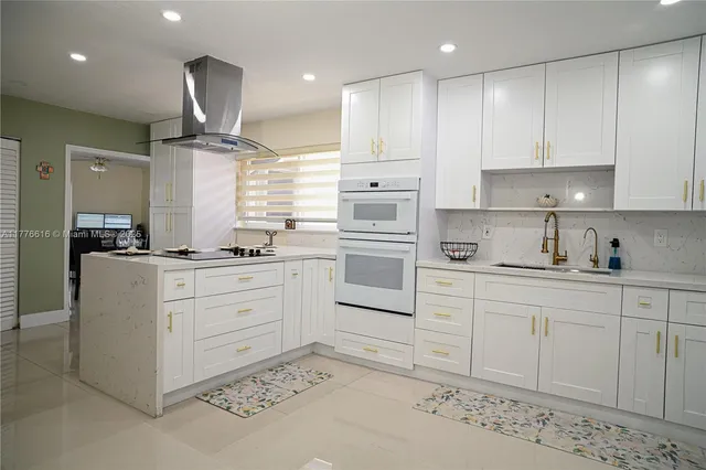 a kitchen with stainless steel appliances granite countertop a stove a sink a refrigerator and white cabinets with wooden floor