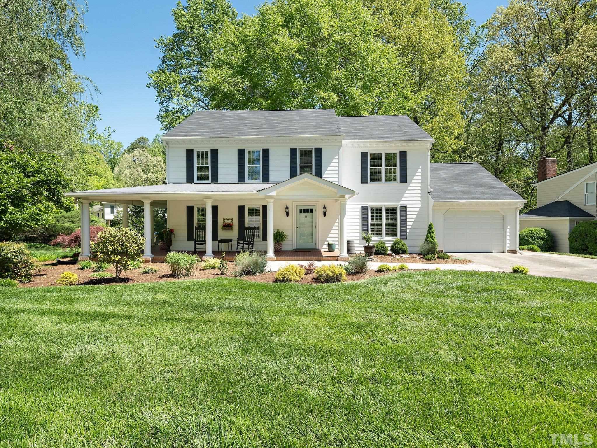 a front view of a house with a garden and trees