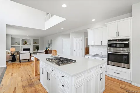 a kitchen with stainless steel appliances kitchen island granite countertop a stove a sink a refrigerator and white cabinets
