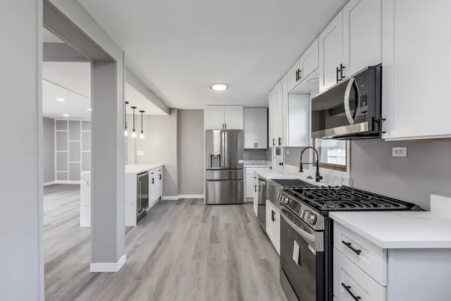 a kitchen with stainless steel appliances granite countertop a stove top oven a sink dishwasher a refrigerator and cabinets with wooden floor