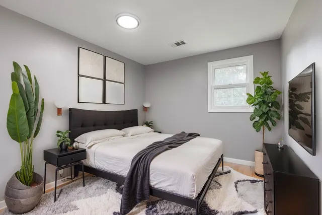 a bedroom with a bed a potted plant and a window