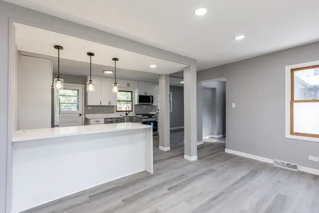 a large kitchen with stainless steel appliances kitchen island a large counter top and a wooden floors