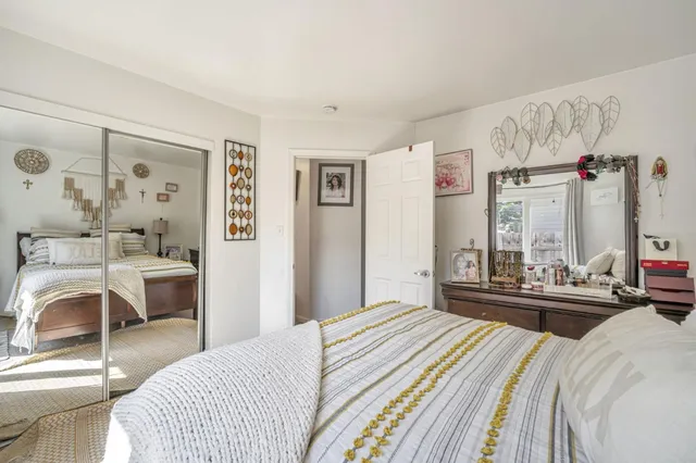 a bedroom with a bed and a large mirror with a dresser