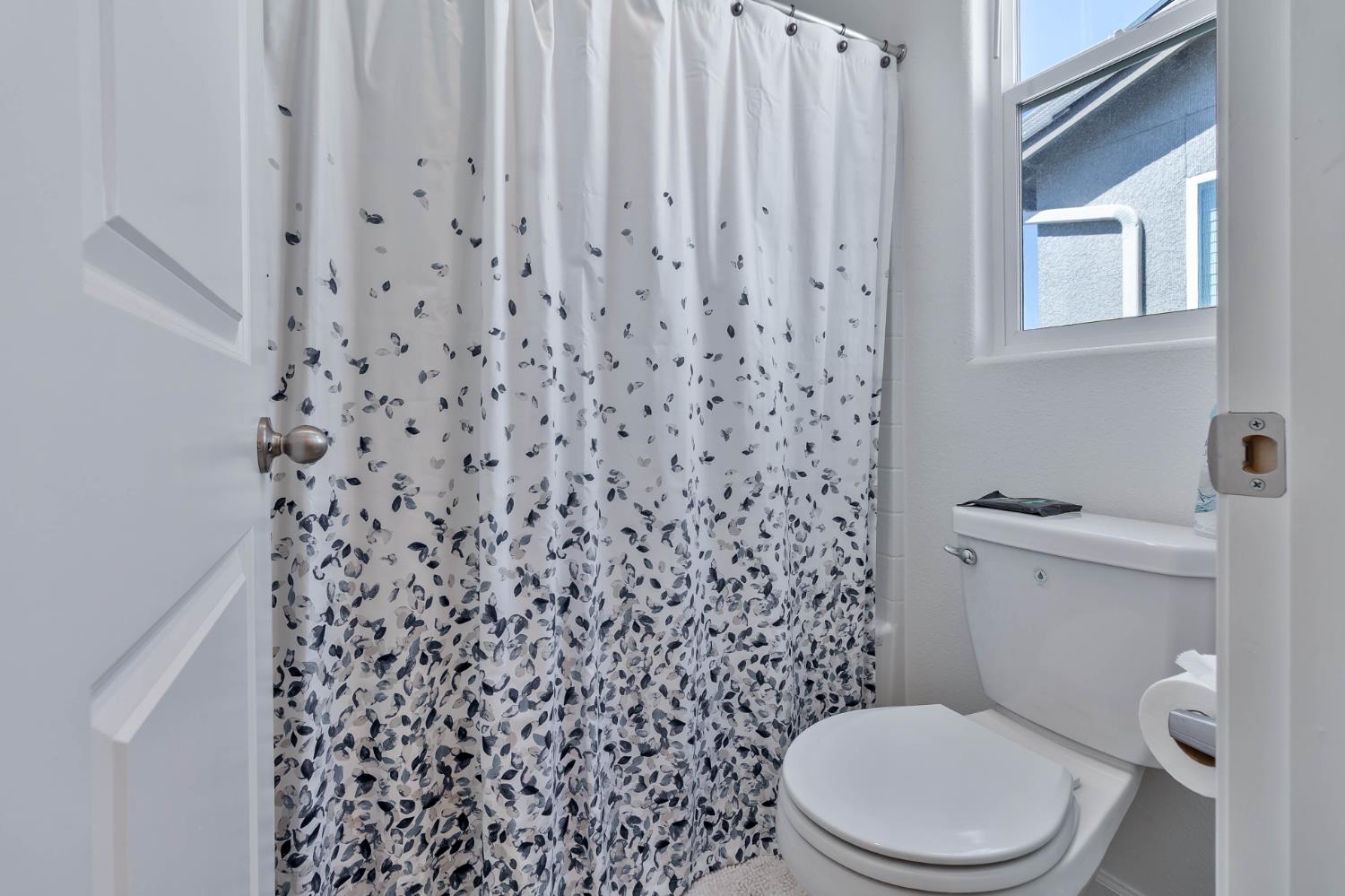 915 Winchell Way West Madera, CA 93636 - Photo 13 of 36 a white toilet sitting next to a shower curtain