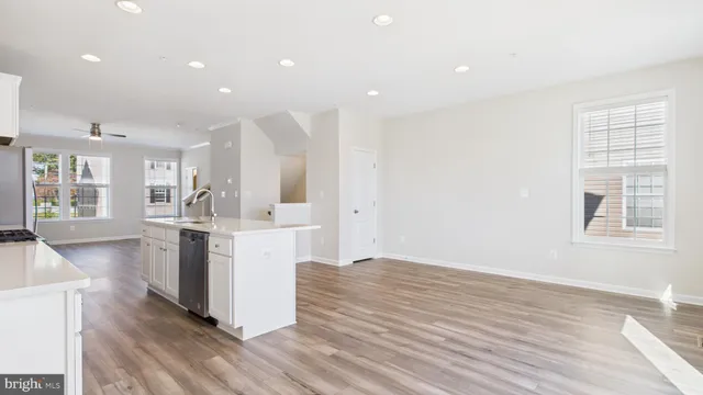 a view of kitchen with stainless steel appliances kitchen island wooden floors and white walls