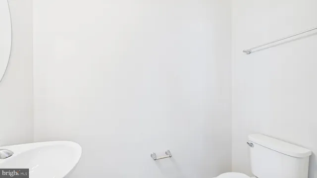 a white toilet sitting next to a white wall