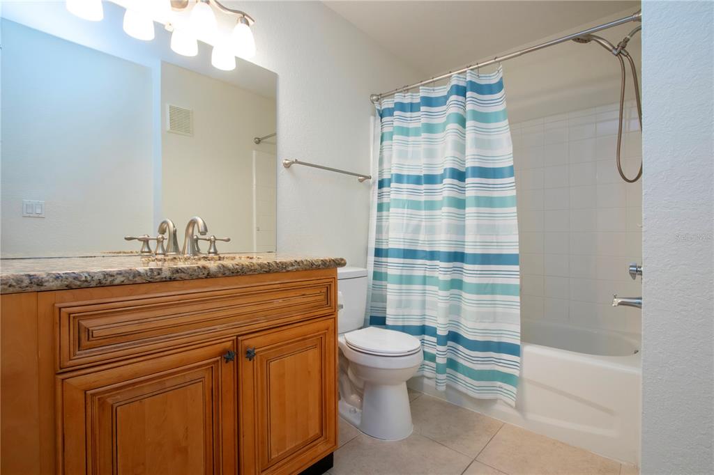 8926 Manor Loop, Unit 107 Lakewood Ranch, FL 34202 - Photo 18 of 44 a bathroom with a granite countertop sink a toilet a mirror and shower