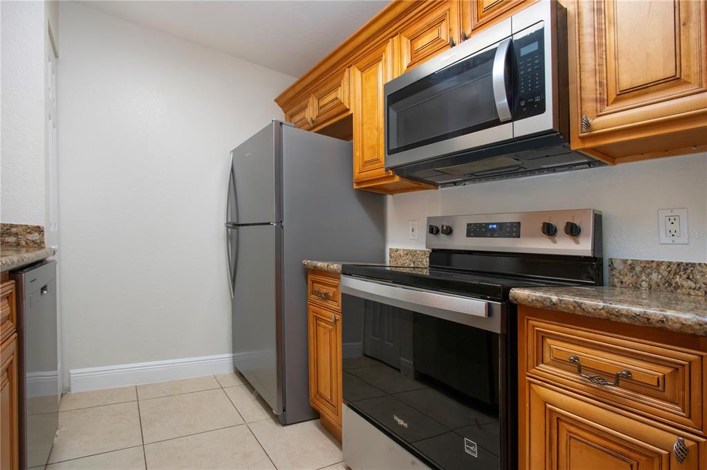 8926 Manor Loop, Unit 107 Lakewood Ranch, FL 34202 - Photo 9 of 44 a kitchen with stainless steel appliances granite countertop a stove and a microwave