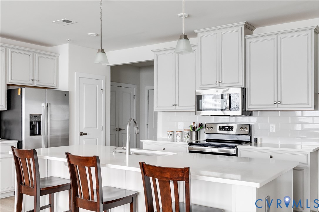 3900 Maze Runner Drive, Unit 206 Midlothian, VA 23112 - Photo 10 of 26 a kitchen with stainless steel appliances kitchen island granite countertop a refrigerator a stove a sink a dining table and chairs with wooden floor