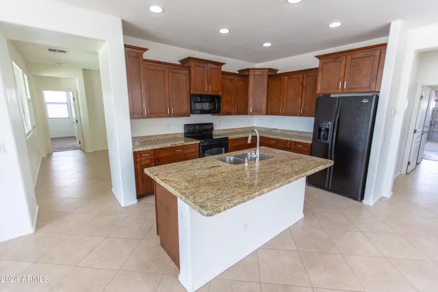 a kitchen with kitchen island granite countertop a sink stove and refrigerator
