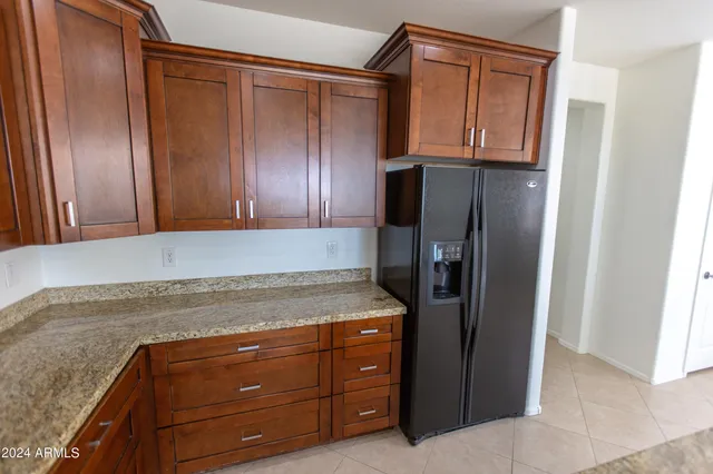 a kitchen with granite countertop a refrigerator and a stove top oven