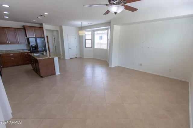 an empty room with windows and chandelier fan