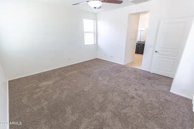 an empty room with windows and chandelier fan