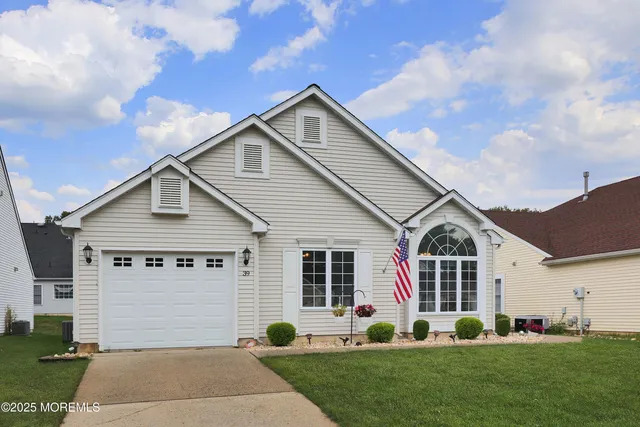 a view of a white house with a small yard and potted plants