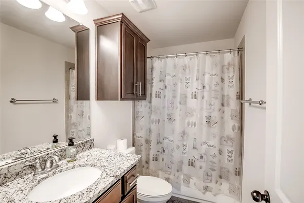 a bathroom with a granite countertop sink toilet and shower