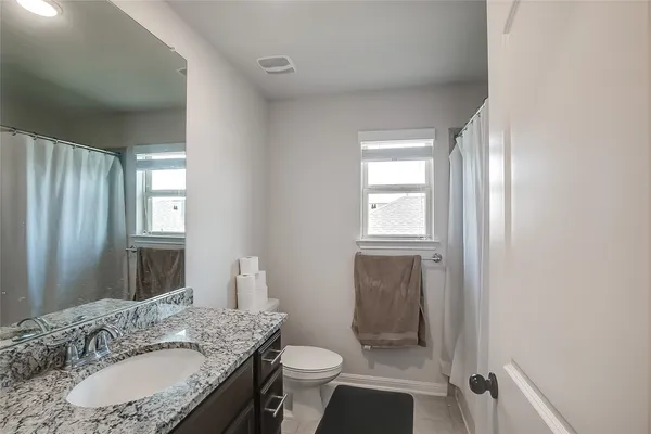 a bathroom with a granite countertop sink toilet and shower