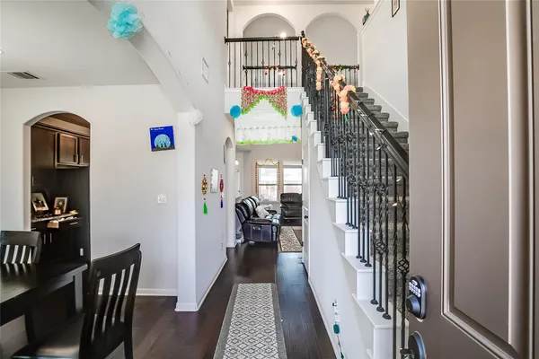 a view of a hallway to a livingroom with wooden floor and furniture