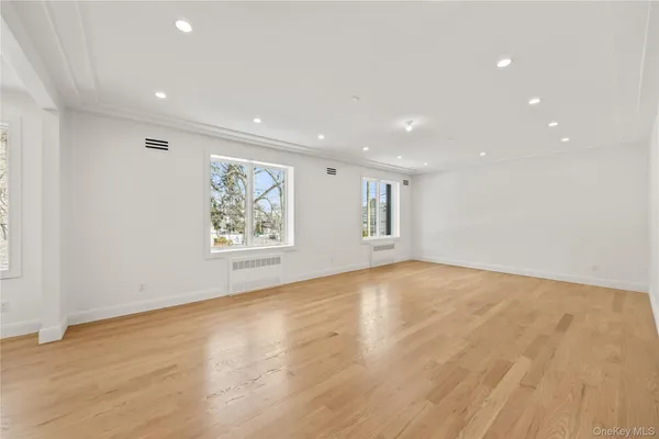 a view of an empty room with wooden floor and window