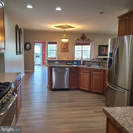 a kitchen with stainless steel appliances granite countertop a refrigerator a stove and a sink