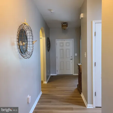 a view of a hallway with wooden floor and a large mirror