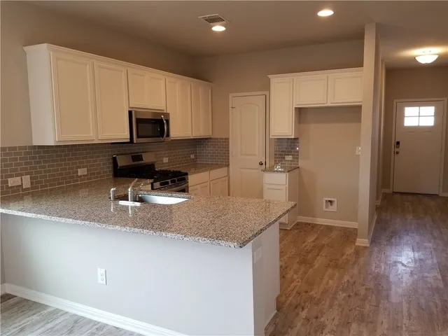 a kitchen with stainless steel appliances granite countertop a refrigerator a sink a stove a microwave and wooden cabinets