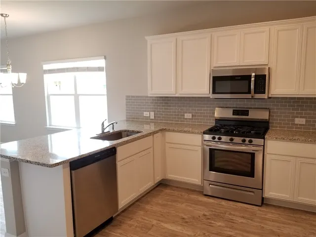 a kitchen with granite countertop a sink a stove and microwave