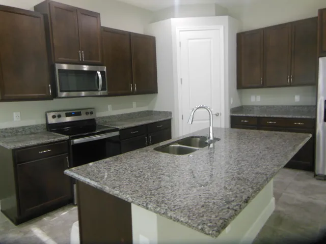 a kitchen with stainless steel appliances granite countertop a sink stove and microwave