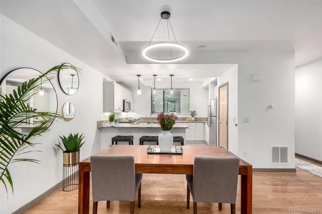 a dining room with wooden floor a chandelier a wooden table and chairs