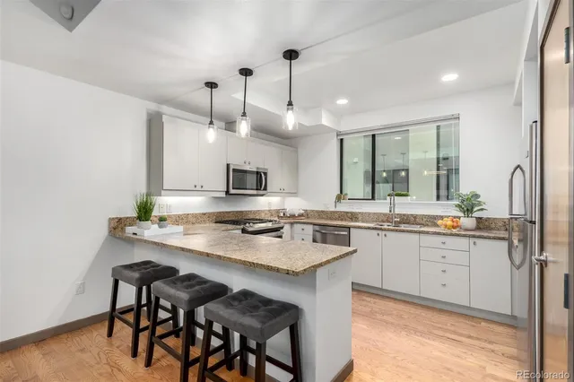 a kitchen with stainless steel appliances kitchen island a white table chairs and a sink