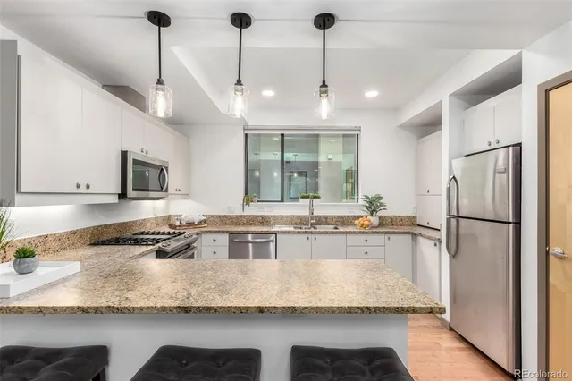 a large kitchen with granite countertop a large counter top stainless steel appliances and cabinets
