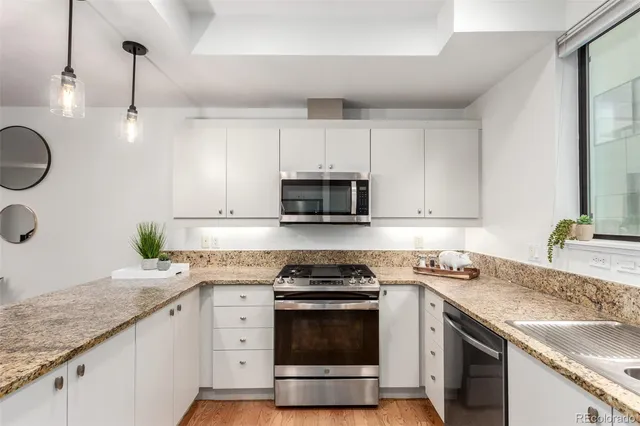 a kitchen with granite countertop a sink stainless steel appliances and white cabinets