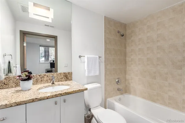 a bathroom with a granite countertop sink a toilet and shower
