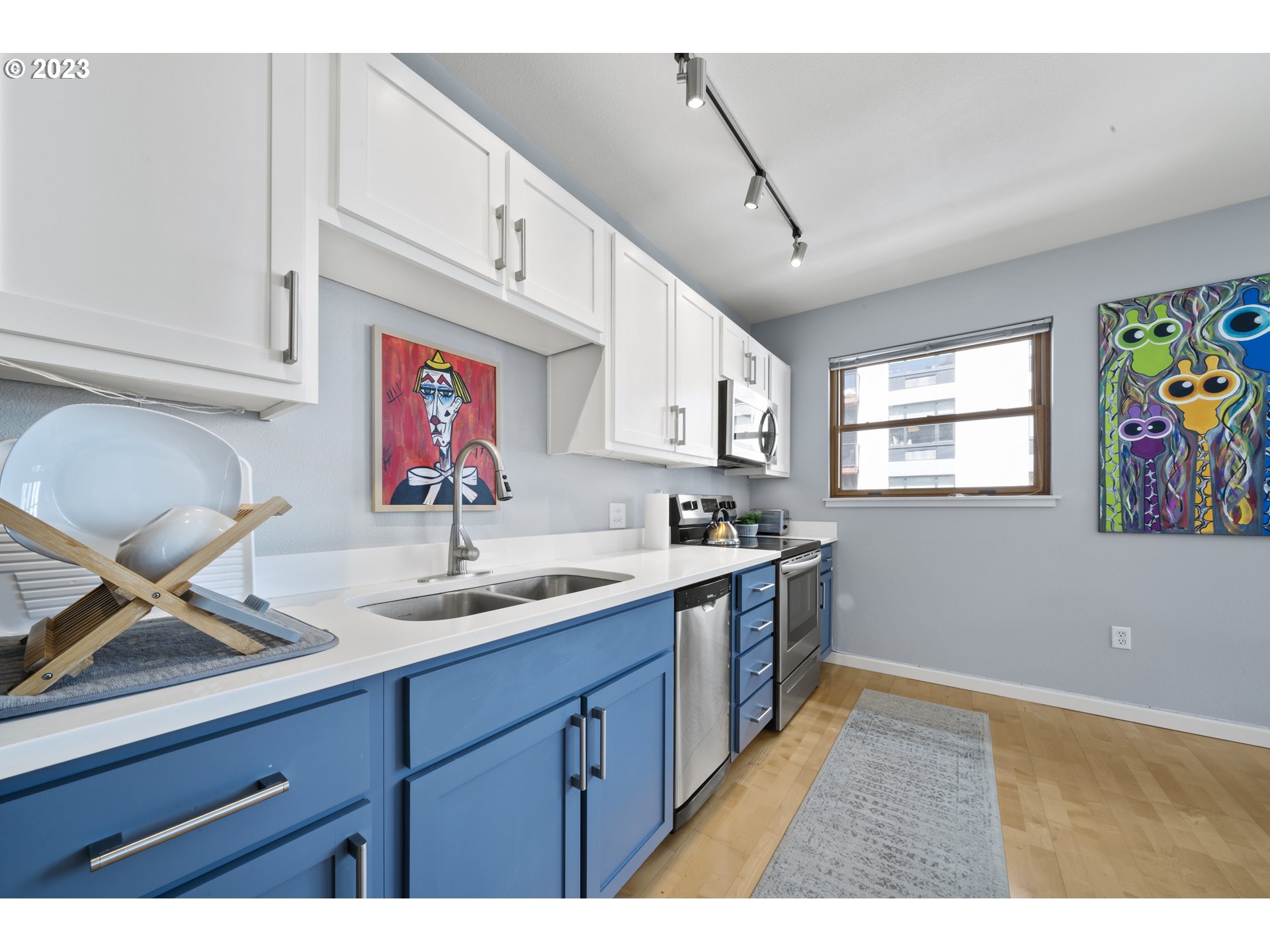 1134 Southwest Jefferson Street, Unit 405 Portland, OR 97201 - Photo 5 of 28 a kitchen with stainless steel appliances granite countertop a sink dishwasher and cabinets with wooden floor