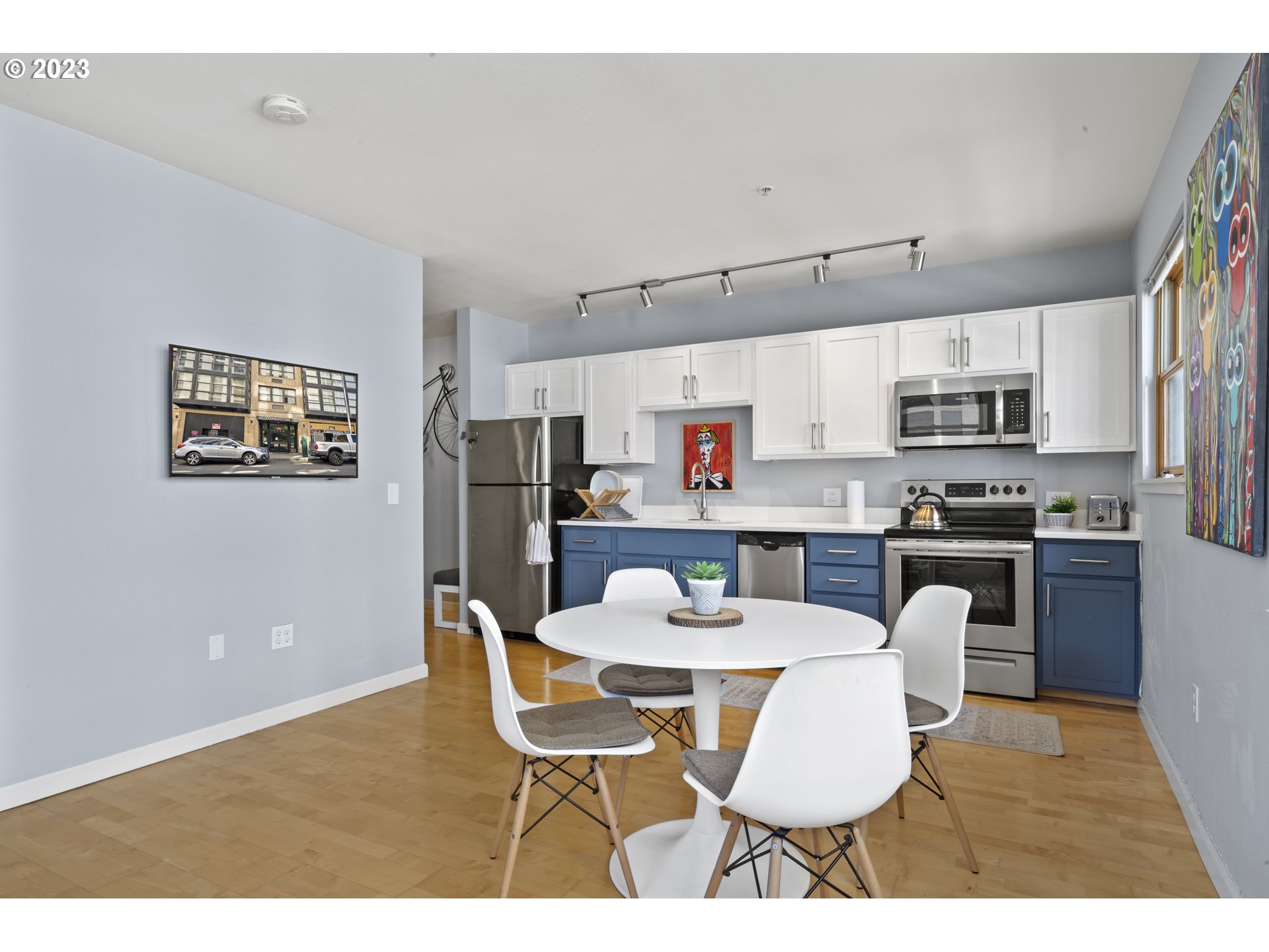 1134 Southwest Jefferson Street, Unit 405 Portland, OR 97201 - Photo 9 of 28 a kitchen with stainless steel appliances kitchen island granite countertop a dining table chairs refrigerator and a sink