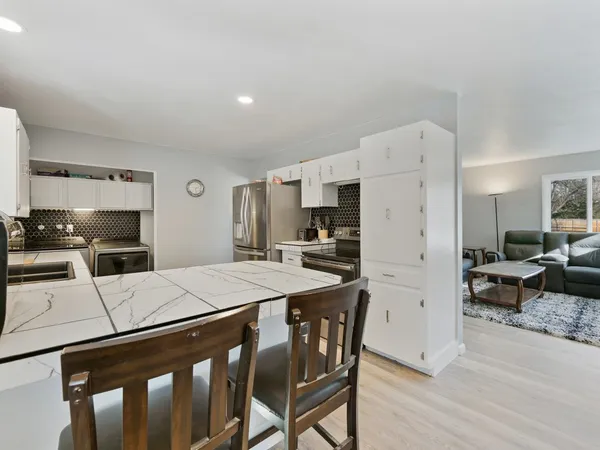 a kitchen with a refrigerator a stove a sink a dining table and chairs