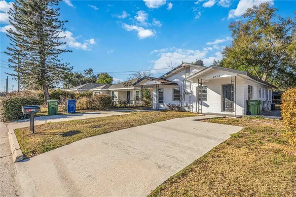 a view of a white house with a large tree