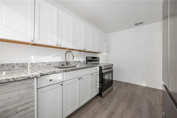 a kitchen with granite countertop white cabinets and white appliances
