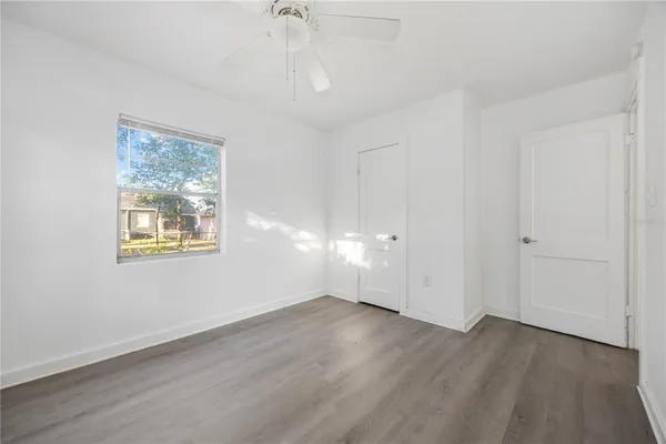 a view of an empty room with wooden floor and a window