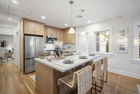 a kitchen with stainless steel appliances granite countertop a refrigerator a sink a stove a dining table and chairs