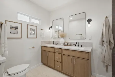 a bathroom with a toilet a sink a mirror a vanity and shower