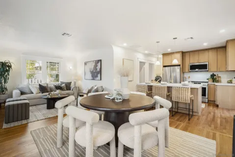 a dining room with furniture a wooden floor and a kitchen view