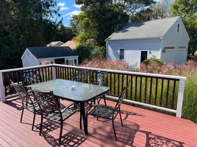 a view of a patio with table and chairs with wooden floor and fence